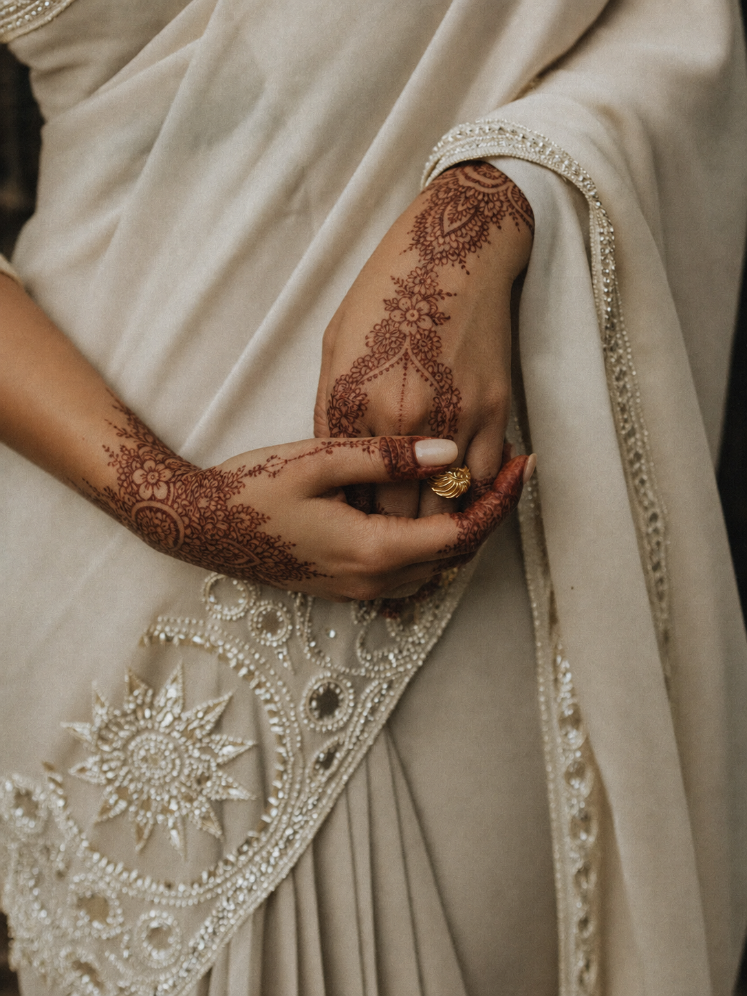 Bride and groom's intertwined hands with henna and a gold wedding ring